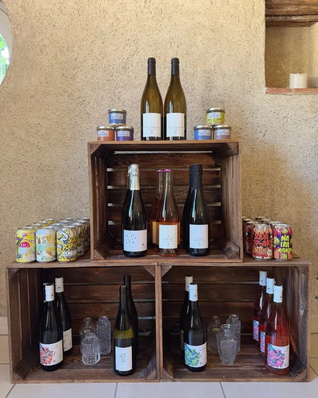 Des caisses en bois garnies de pots, de terrines et de conserves artisanales, contre le mur de la maison