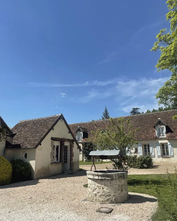 Le puits en pierre au milieu de la cour de gravier